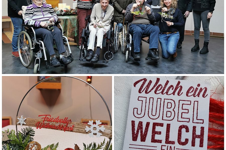 Gruppe von Menschen, einige im Rollstuhl, in einem Raum mit religiösen Bildern. Weihnachtskranz mit roten Kugeln, Tannenzweigen und Schriftzug 'Friedvolle Weihnachten'. Stoff mit rotem Schriftzug 'Welch ein Jubel Welch ein Leben'.