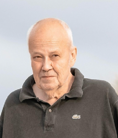 Porträt eines lächelnden Mannes mit hellen Haaren und hellem Hemd vor unscharfem Hintergrund