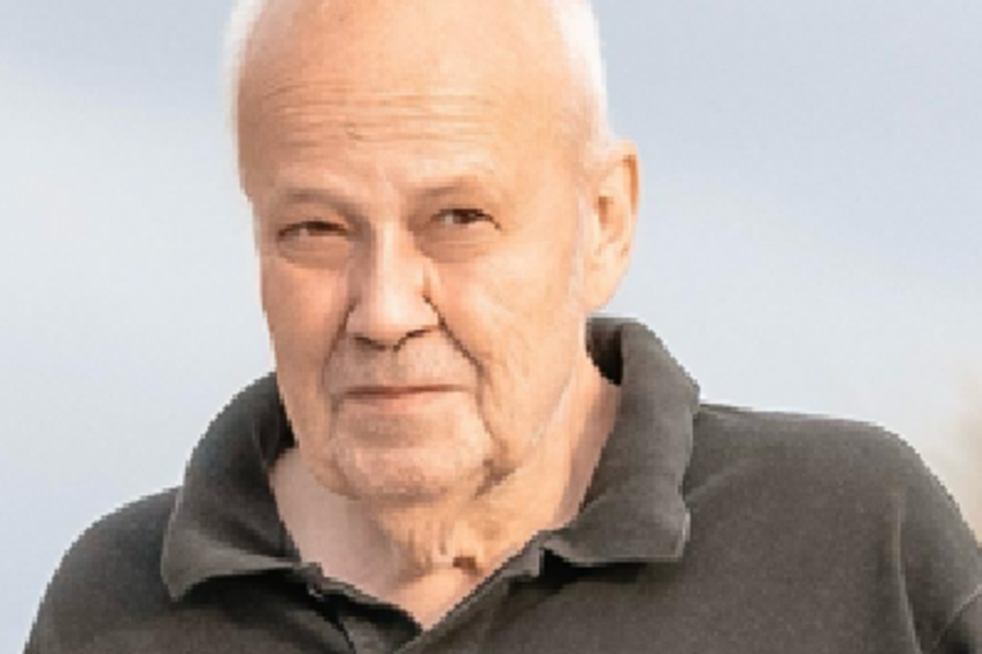 Porträt eines lächelnden Mannes mit hellen Haaren und hellem Hemd vor unscharfem Hintergrund